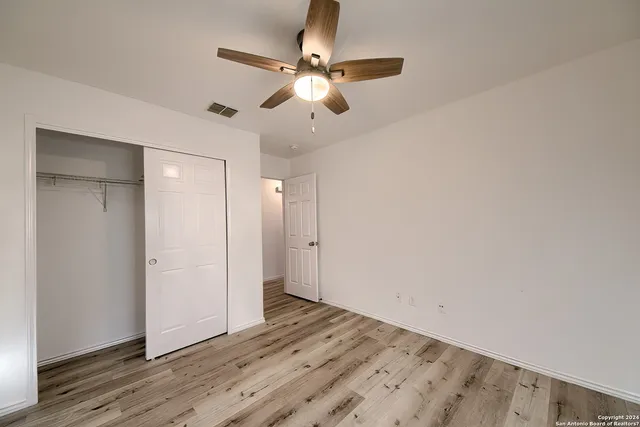 an empty room with wooden floor and ceiling fan
