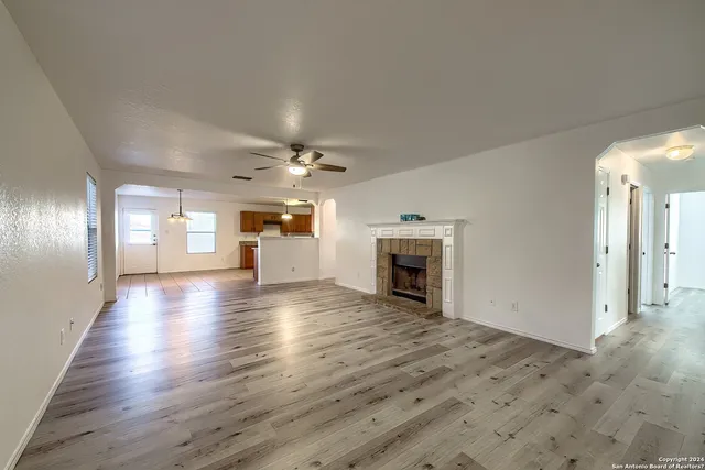 an empty room with wooden floor fireplace and windows