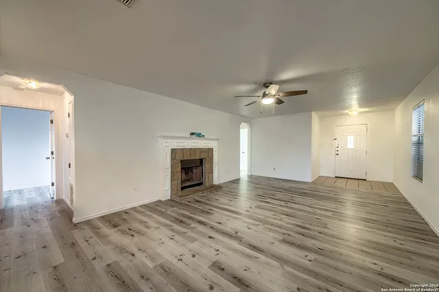 a view of an empty room with wooden floor and a fireplace