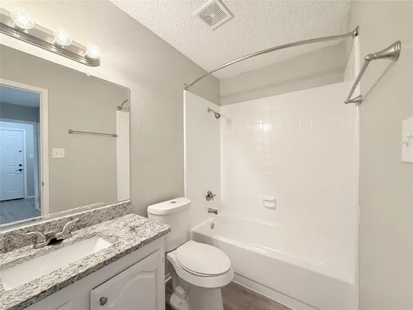 a bathroom with a granite countertop sink a toilet and shower
