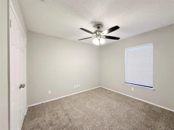 an empty room with a chandelier fan and windows