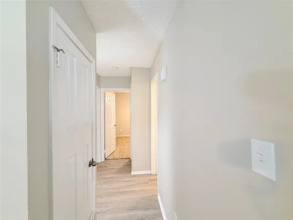 a view of a hallway with wooden floor and a bathroom