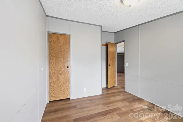 a view of an empty room with wooden floor and a bathroom