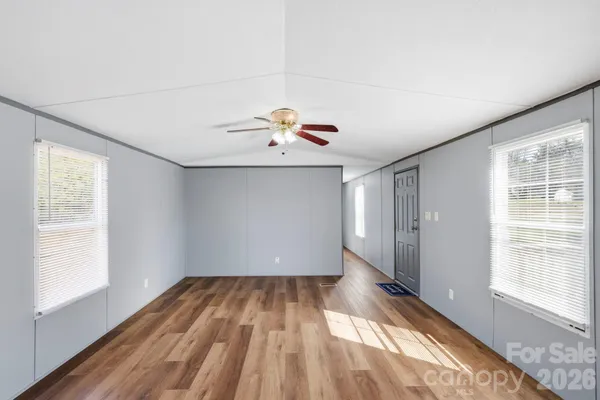a view of empty room with wooden floor and fan