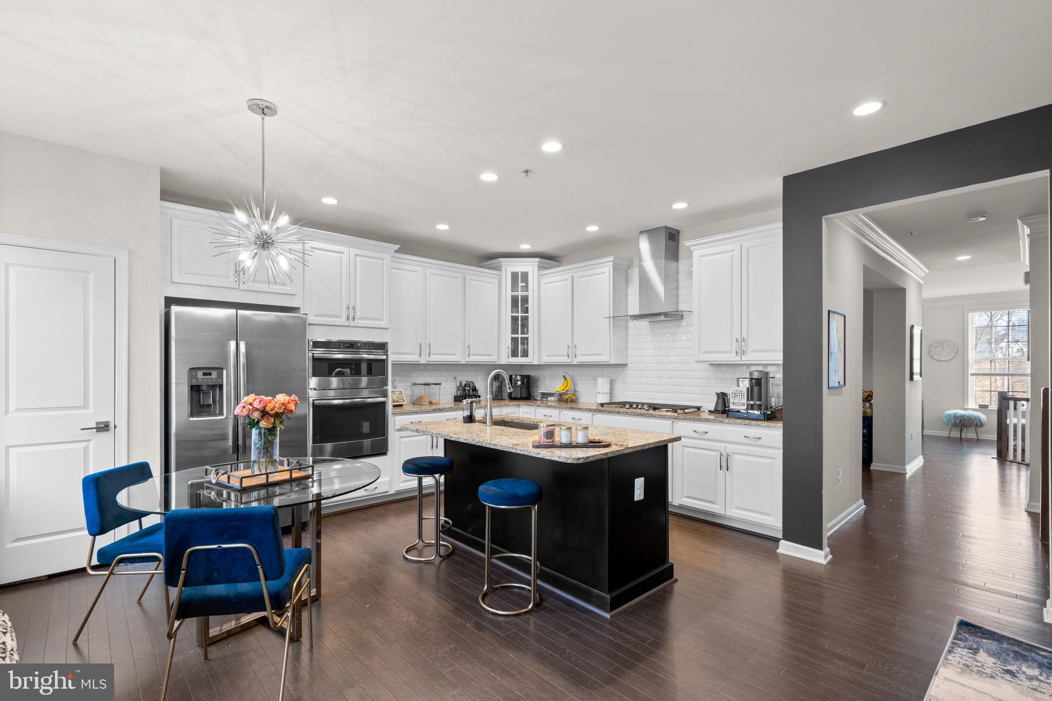 4323 Spring Foal Court Upper Marlboro, MD 20772 - Photo 15 of 49 a kitchen with stainless steel appliances granite countertop a stove top oven a refrigerator a dining table and chairs with wooden floor