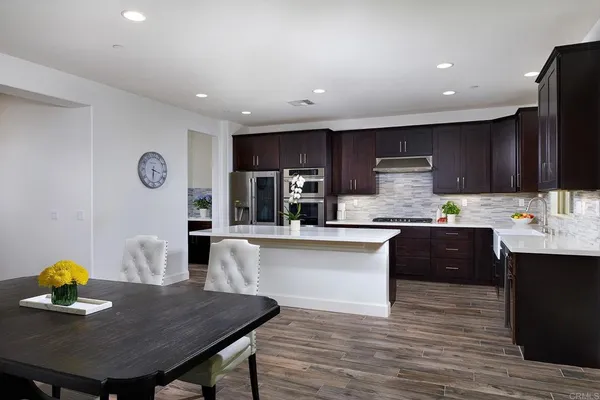 a kitchen with granite countertop a table chairs a sink dishwasher stove and cabinets with wooden floor