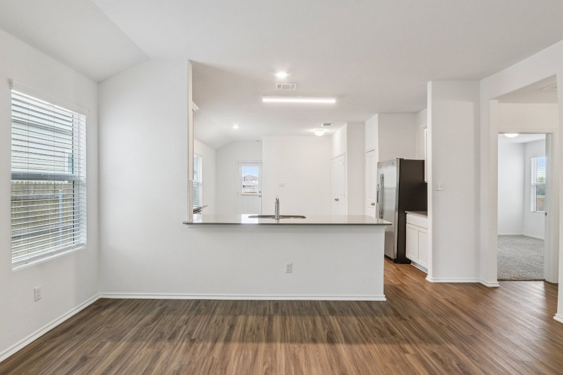 240 Line Of Fire Way Jarrell, TX 76537 - Photo 6 of 33 Kitchen with healthy amount of natural light, white cabinets, a peninsula, and freestanding refrigerator