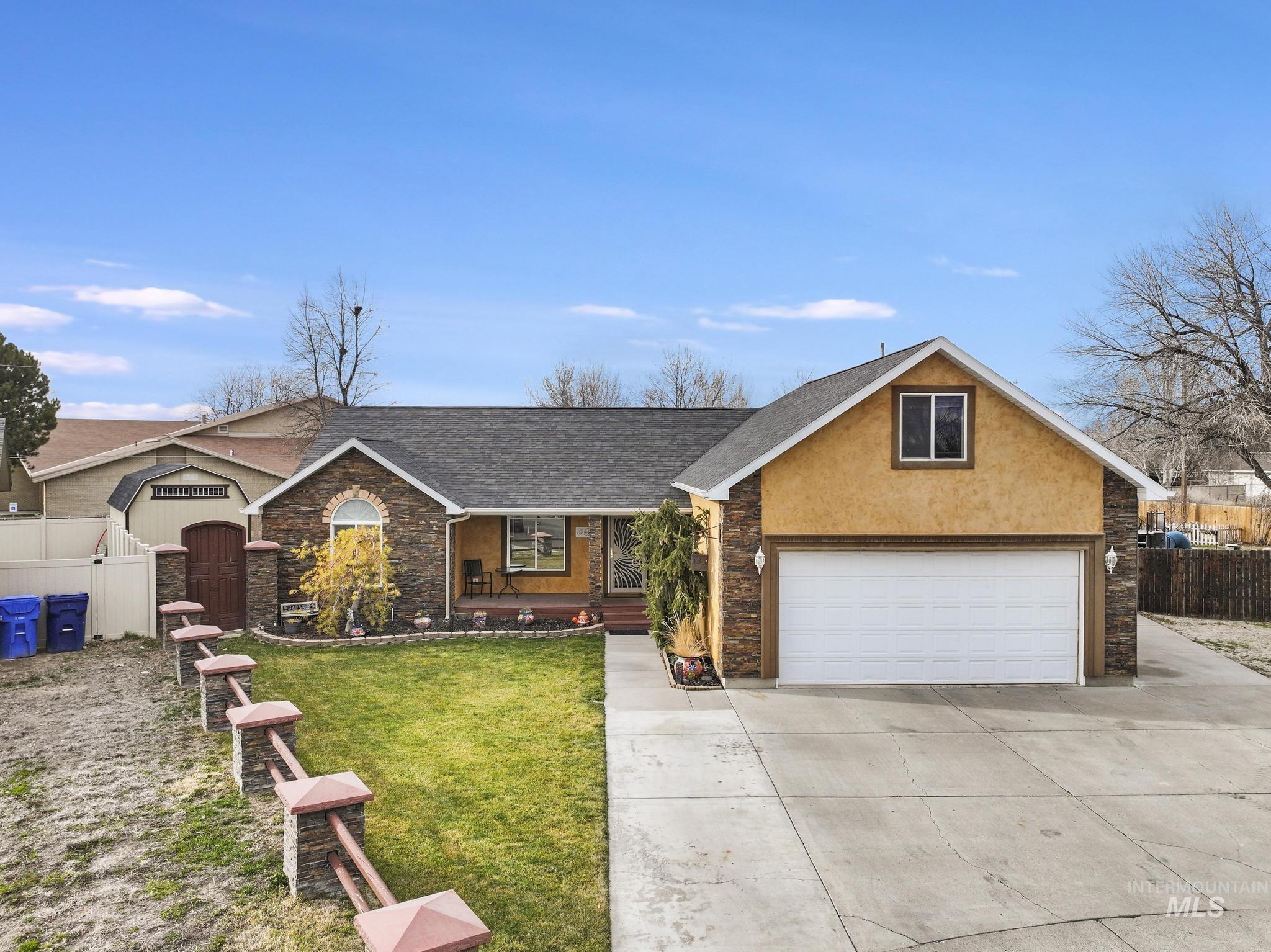 733 Beta Circle Twin Falls, ID 83301 - Photo 2 of 50 View of front facade featuring stone siding, a shingled roof, concrete driveway, a porch, and stucco siding