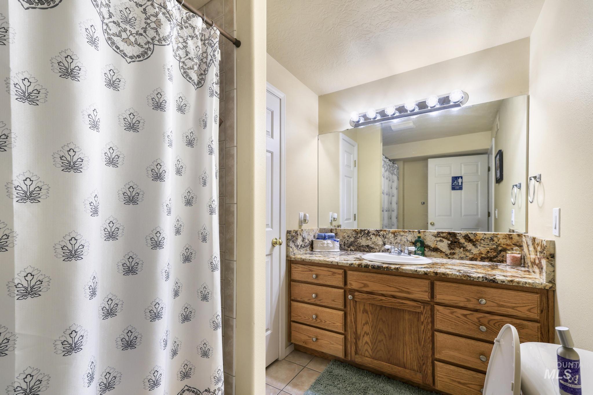 733 Beta Circle Twin Falls, ID 83301 - Photo 30 of 50 Bathroom with vanity, a shower with shower curtain, light tile patterned flooring, and a textured ceiling