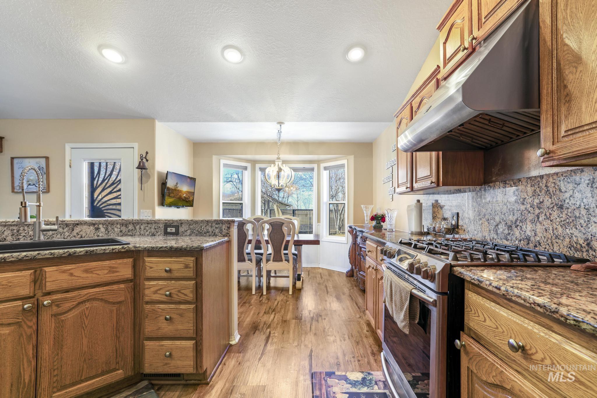 733 Beta Circle Twin Falls, ID 83301 - Photo 7 of 50 Kitchen featuring stainless steel gas range, wood finish cabinetry, tasteful backsplash, light wood-style floors, and a textured ceiling