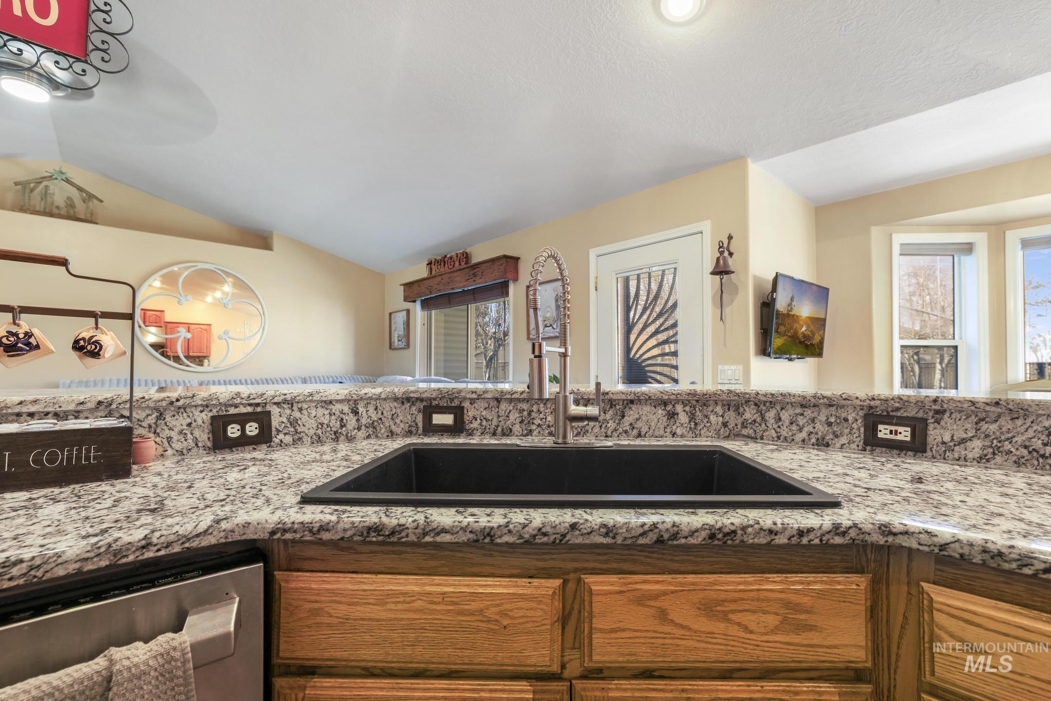 733 Beta Circle Twin Falls, ID 83301 - Photo 9 of 50 Kitchen with wood finish cabinets, light stone countertops, dishwasher, and lofted ceiling