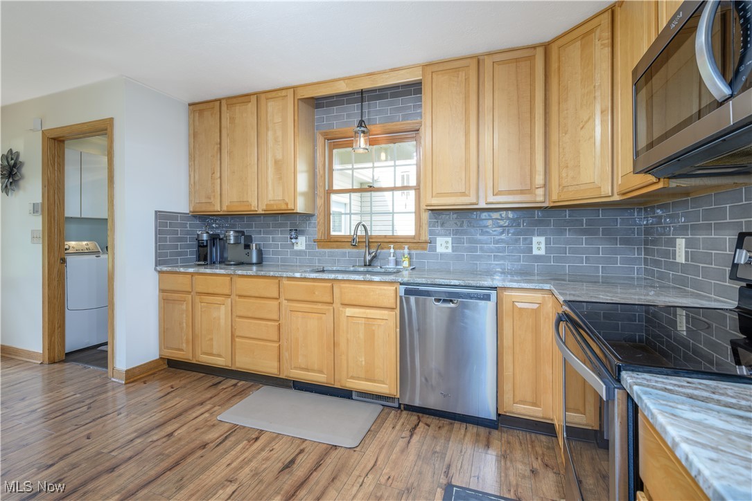 6640 Giddings Road Rootstown, OH 44272 - Photo 35 of 49 Kitchen featuring stainless steel appliances, backsplash, light wood-style floors, washer / dryer, and light stone counters