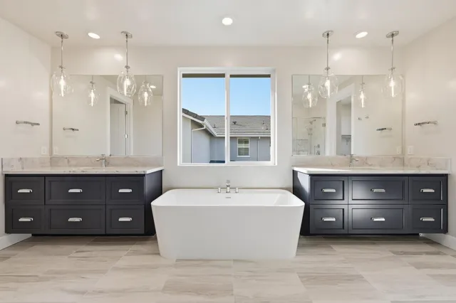 a spacious bathroom with a tub double sink shower and mirror