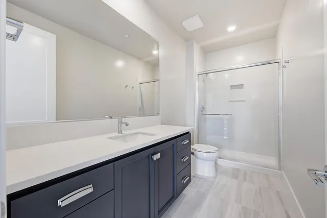 a bathroom with a granite countertop sink a toilet and shower