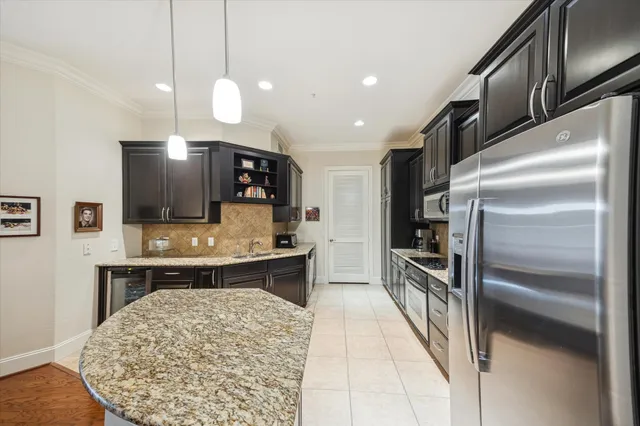 a large kitchen with stainless steel appliances kitchen island granite countertop a stove a sink dishwasher and a refrigerator with wooden floor
