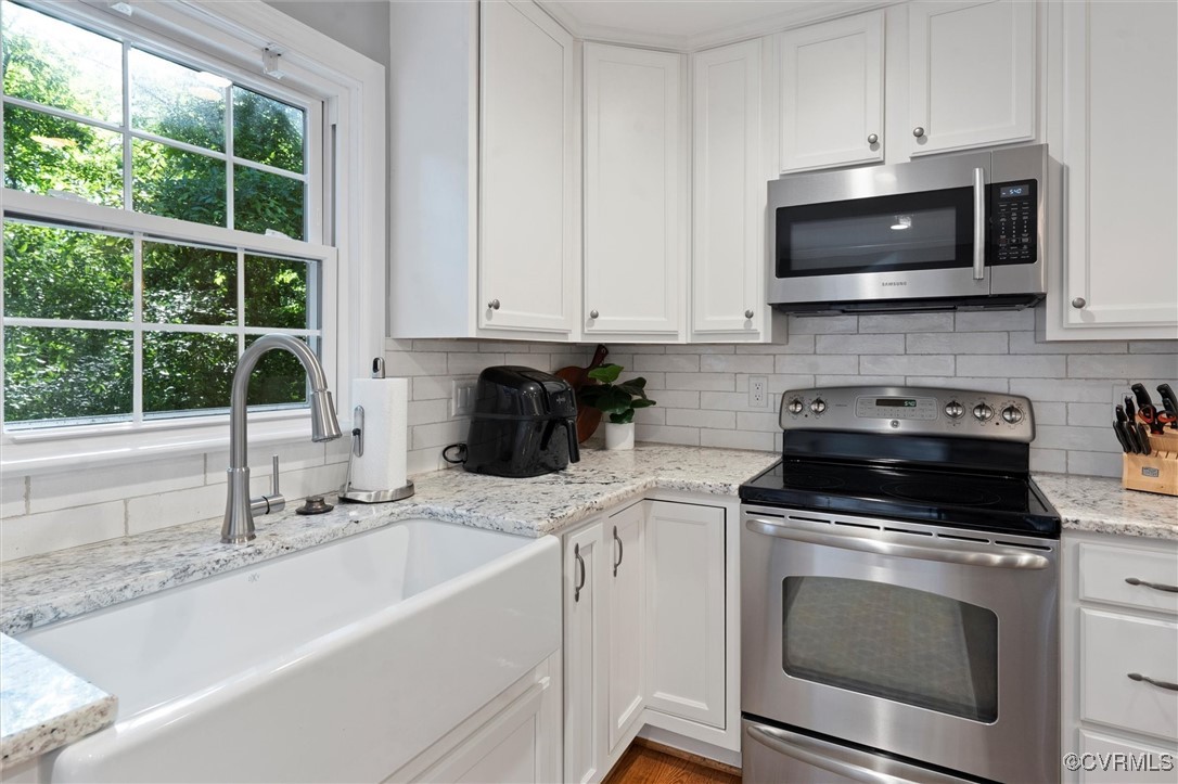 4107 Poplar Grove Road Midlothian, VA 23112 - Photo 26 of 38 a kitchen with stainless steel appliances granite countertop a sink a stove a microwave and wooden cabinets