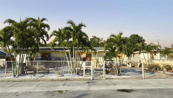 a view of a brick house with large windows and palm trees