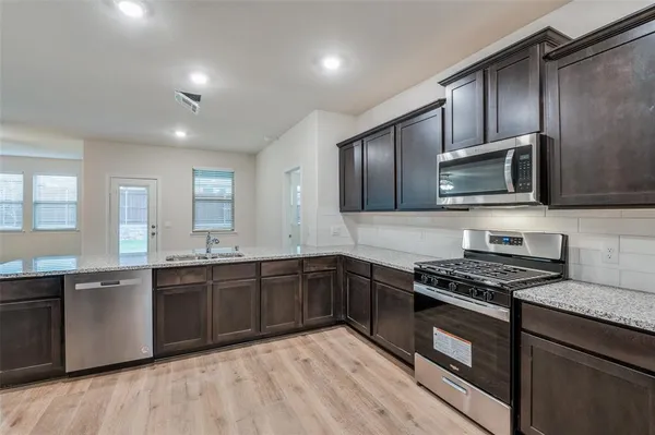 a kitchen with stainless steel appliances granite countertop wooden cabinets a stove top oven a sink and dishwasher