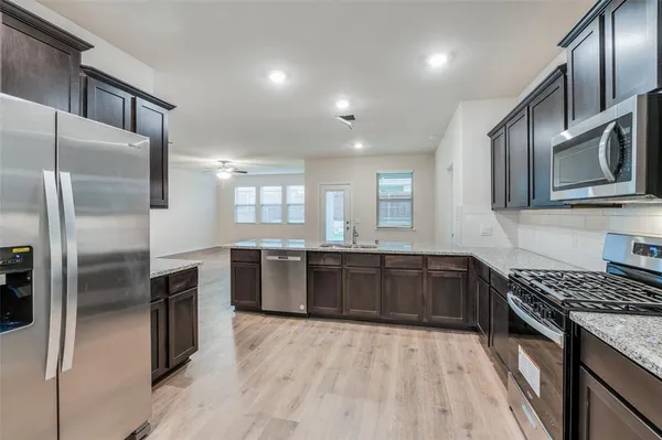a kitchen with stainless steel appliances granite countertop a refrigerator a stove top oven and sink