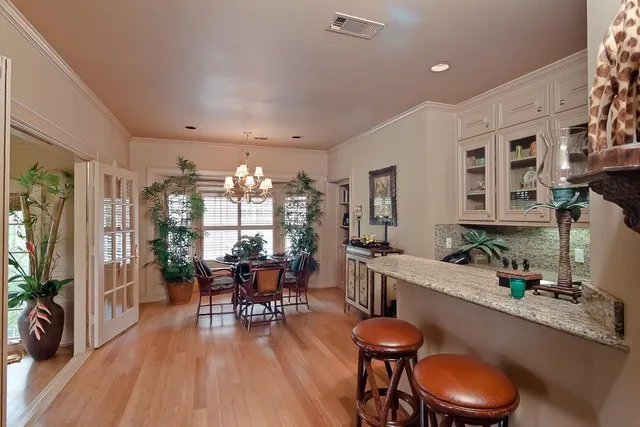 a dining room with wooden floor a chandelier a wooden table and chairs