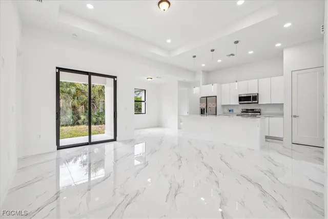 a view of kitchen with stainless steel appliances kitchen island granite countertop a stove top oven a sink a refrigerator and white cabinets with wooden floor