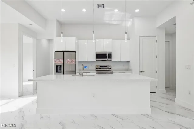 a large white kitchen with stainless steel appliances