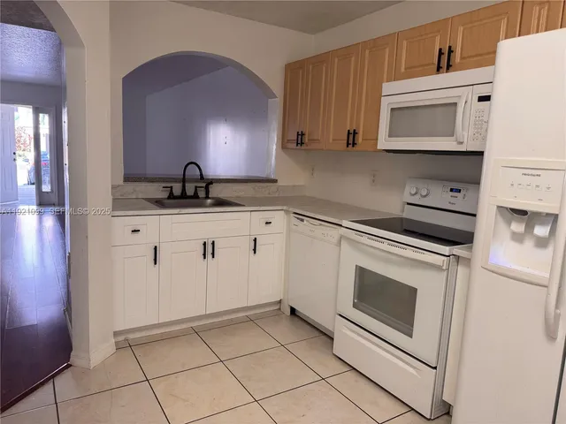 a kitchen with granite countertop white cabinets and white appliances