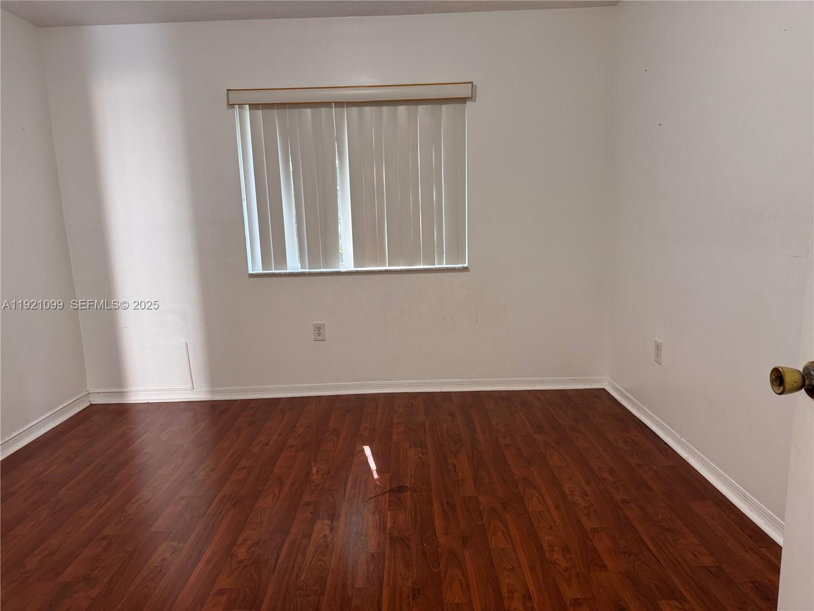 1260 Southeast 31st Court, Unit 10334 Homestead, FL 33035 - Photo 6 of 8 a view of an empty room with wooden floor and a window