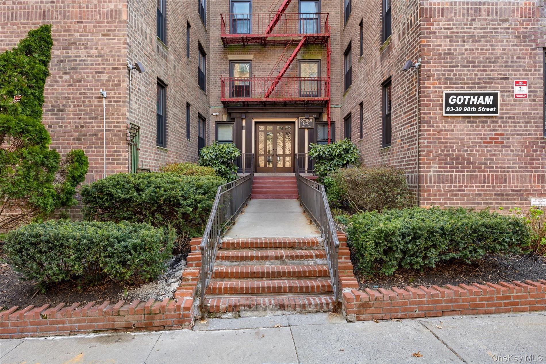 83-30 98th Street, Unit 1H Queens, NY 11421 - Photo 17 of 18 front view of a brick house with a yard
