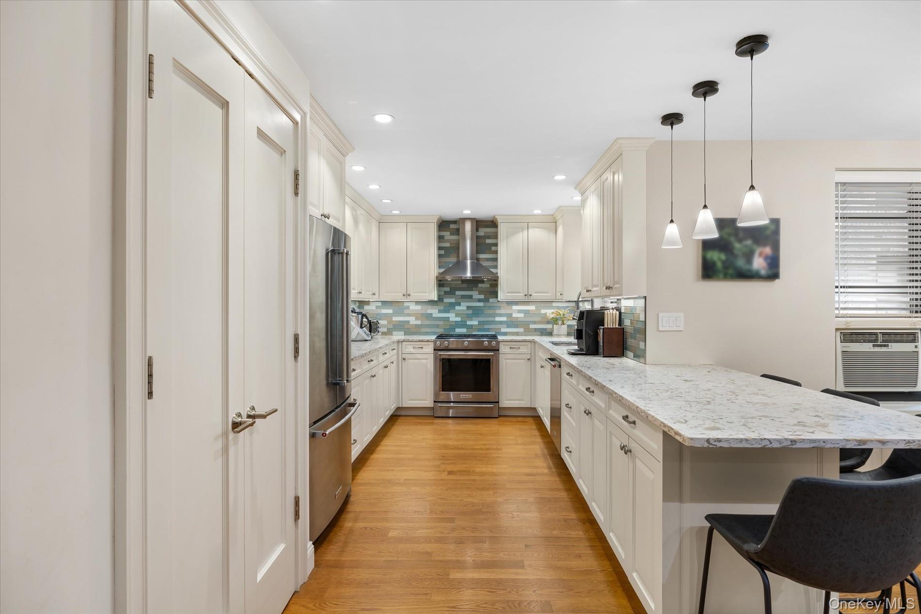 83-30 98th Street, Unit 1H Queens, NY 11421 - Photo 2 of 18 a large kitchen with kitchen island granite countertop a stove a sink a refrigerator and a dining table with wooden floor