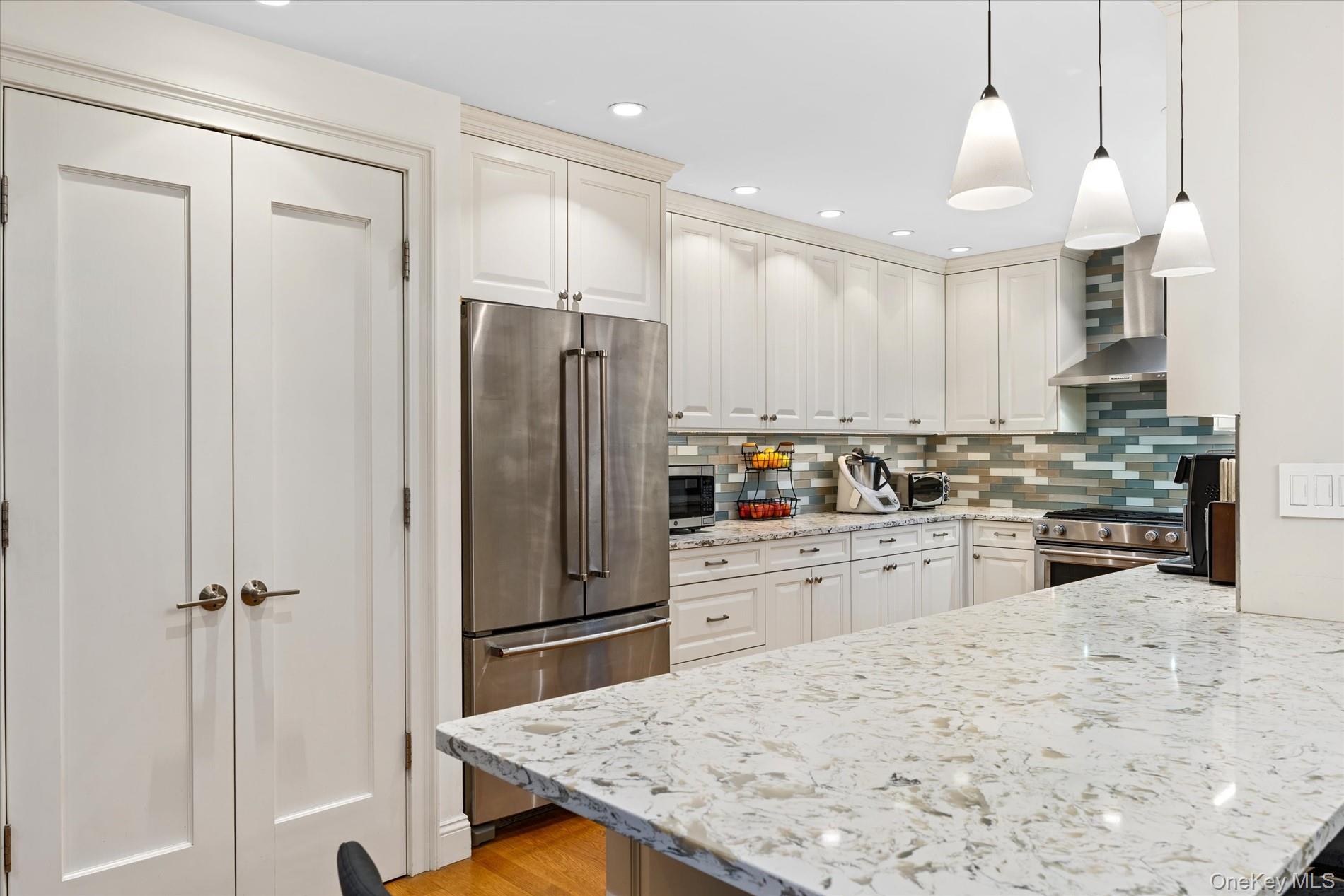 83-30 98th Street, Unit 1H Queens, NY 11421 - Photo 3 of 18 a kitchen with stainless steel appliances kitchen island granite countertop a refrigerator a sink a stove and white cabinets with wooden floor
