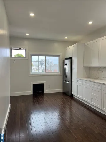 an empty room with wooden floor cabinet and windows