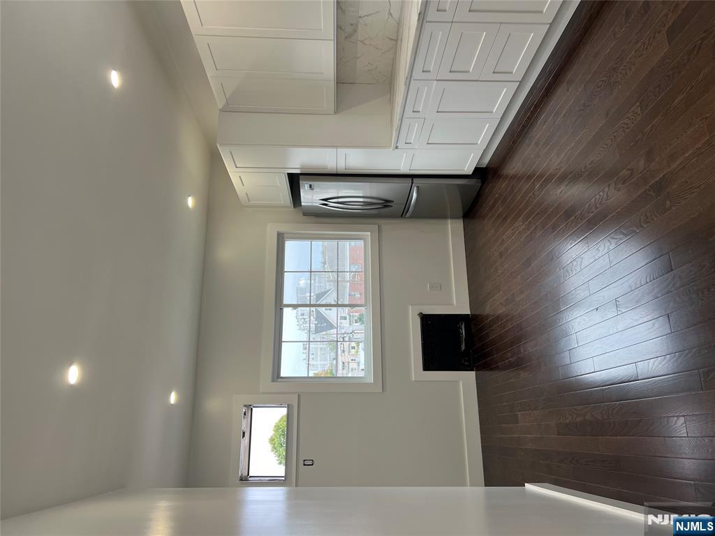 34 Garretson Avenue, Unit 2 Bayonne, NJ 07002 - Photo 2 of 12 an empty room with wooden floor cabinet and windows
