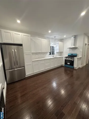 a large kitchen with a center island wooden floor and stainless steel appliances