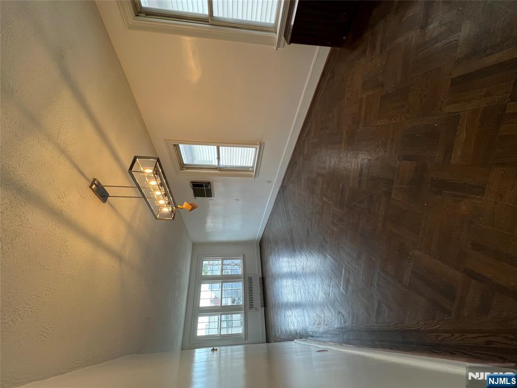 34 Garretson Avenue, Unit 2 Bayonne, NJ 07002 - Photo 5 of 12 an empty room with wooden floor and windows