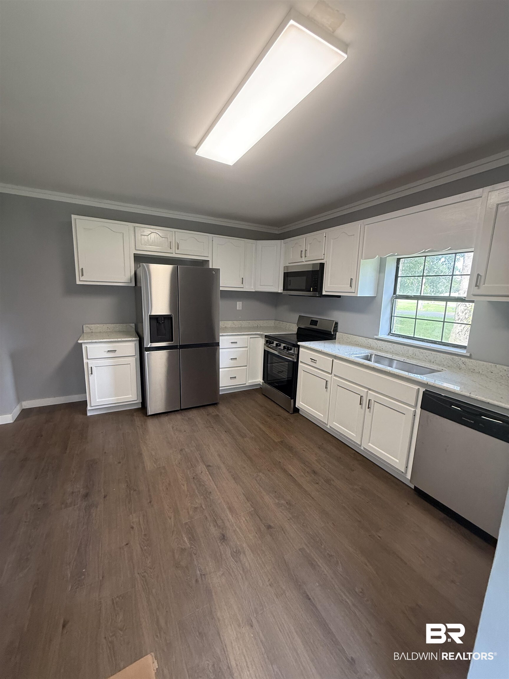 17440 Old Brady Road Bay Minette, AL 36507 - Photo 4 of 9 Kitchen with white cabinetry, stainless steel appliances, dark wood-type flooring, crown molding, and light stone counters