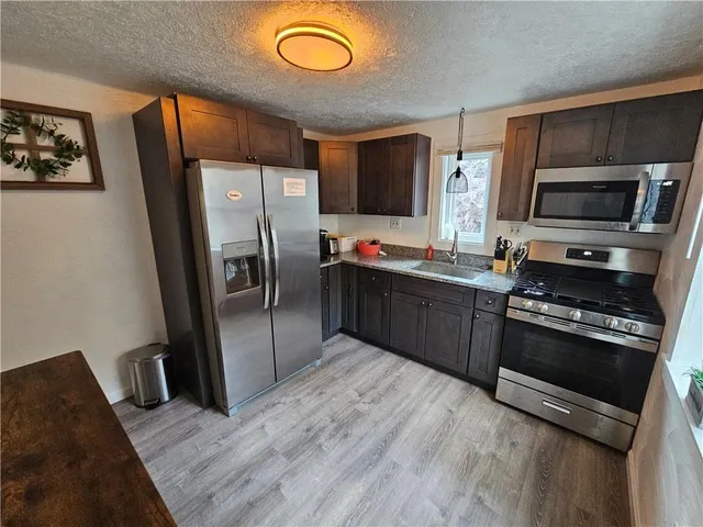 a kitchen with a refrigerator a stove and a wooden floor