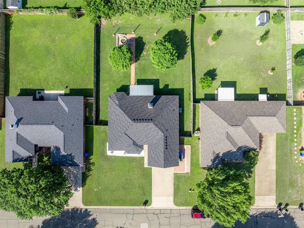 10512 Whitney Trace Drive Waco, TX 76708 - Photo 16 of 39 Aerial perspective showcasing the property's roofline, a large paved driveway, and a spacious green lawn