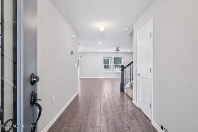 a view of an empty room with a window and wooden floor