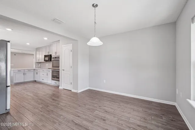 an empty room with windows and chandelier fan