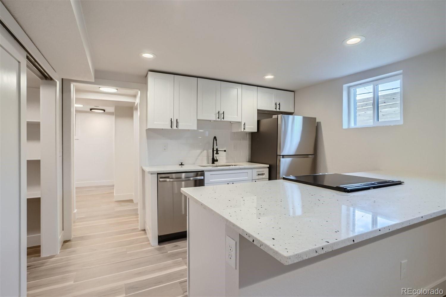 1400 Perry Street Denver, CO 80204 - Photo 19 of 26 a kitchen that has a refrigerator a stove and white cabinets with wooden floor