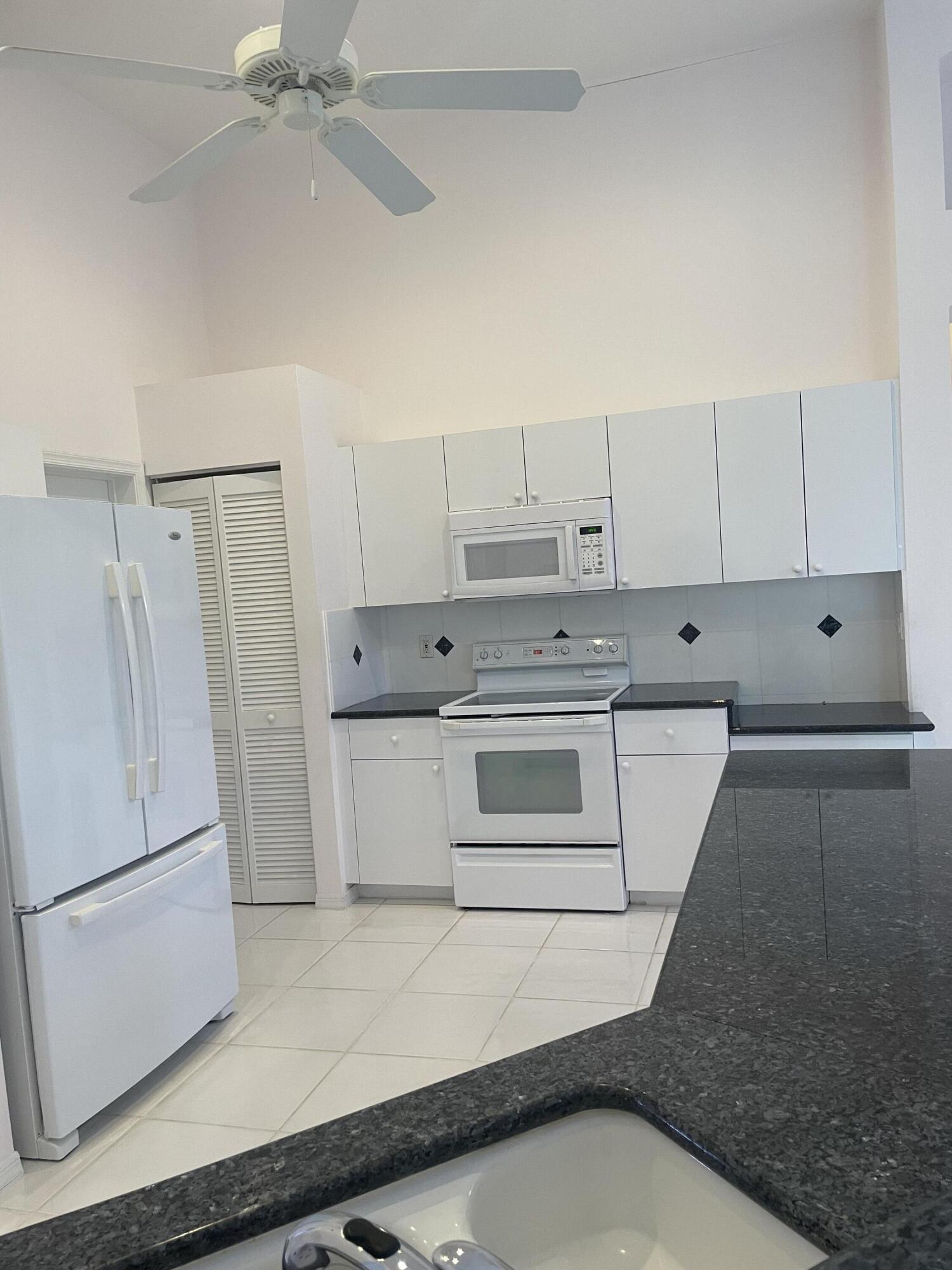 22324 Rushmore Place Boca Raton, FL 33428 - Photo 7 of 33 a kitchen with white cabinets and white appliances