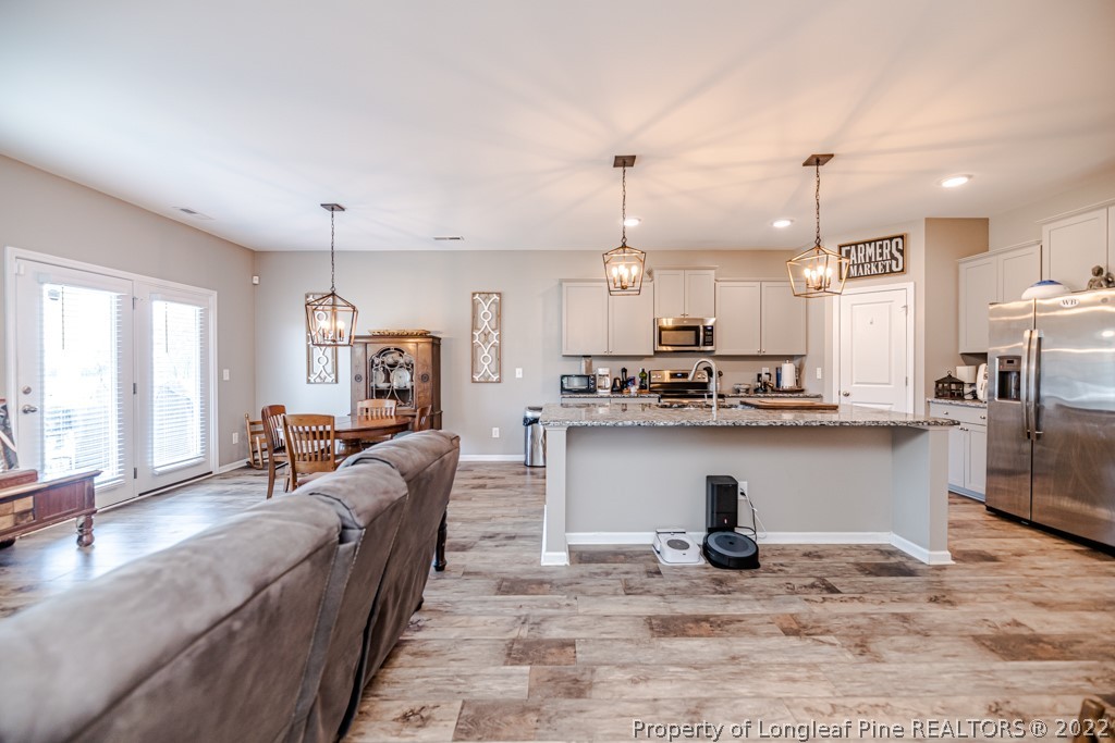 877 Carolina Road Aberdeen, NC 28315 - Photo 15 of 24 a kitchen with stainless steel appliances granite countertop a refrigerator a stove a sink dishwasher and a dining table with wooden floor