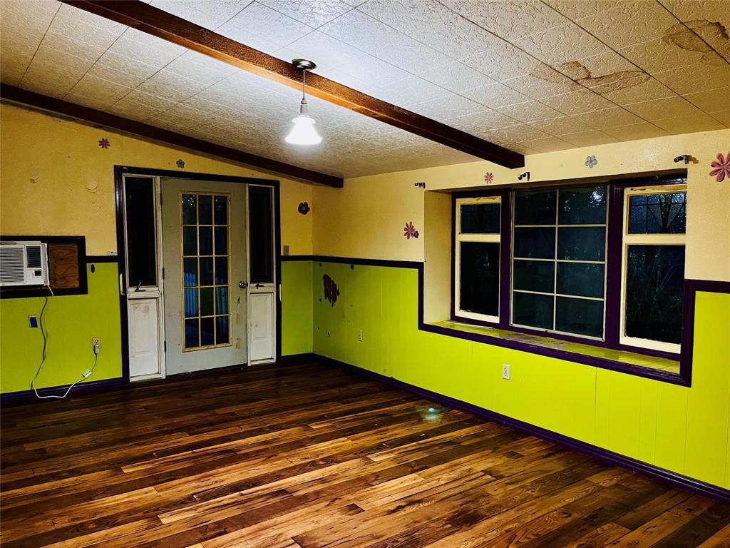 701 County Road 319 Early, TX 76802 - Photo 13 of 33 Empty room featuring dark wood-type flooring, beam ceiling, wainscoting, a wall mounted air conditioner, and wood walls