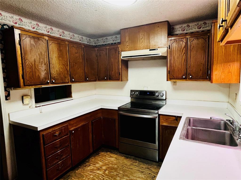 701 County Road 319 Early, TX 76802 - Photo 14 of 33 Kitchen with stainless steel electric range oven, a textured ceiling, light countertops, range hood, and dark brown cabinetry