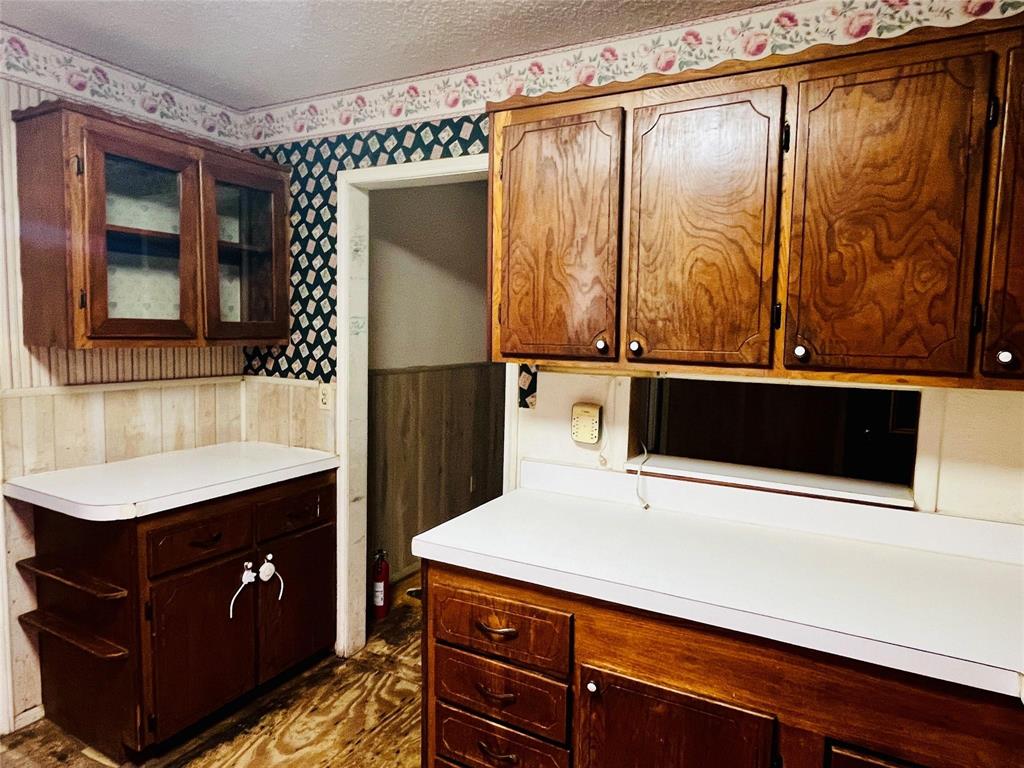 701 County Road 319 Early, TX 76802 - Photo 15 of 33 Kitchen featuring a wainscoted wall, wallpapered walls, wood walls, light countertops, and a textured ceiling