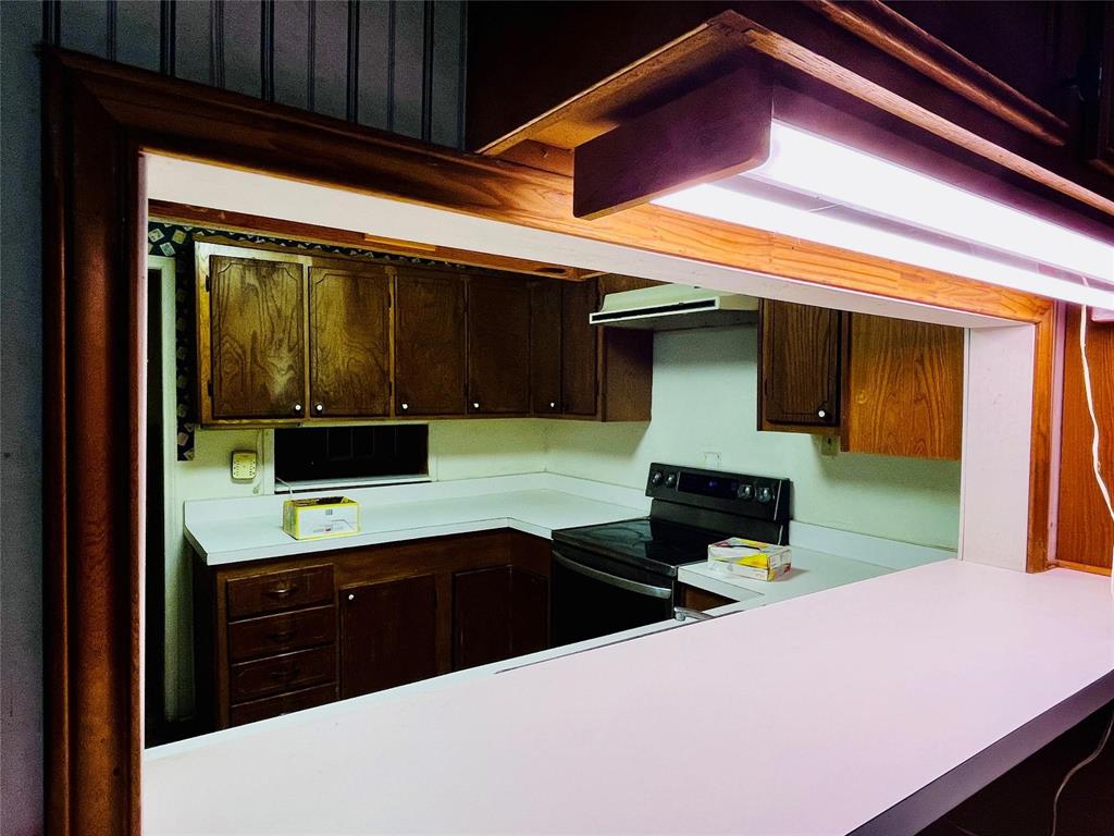 701 County Road 319 Early, TX 76802 - Photo 17 of 33 Kitchen with light countertops, dark brown cabinets, electric range, built in study area, and under cabinet range hood