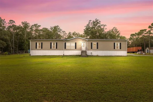 a front view of house with yard and trees in the background