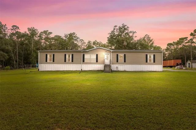a front view of house with yard and trees in the background