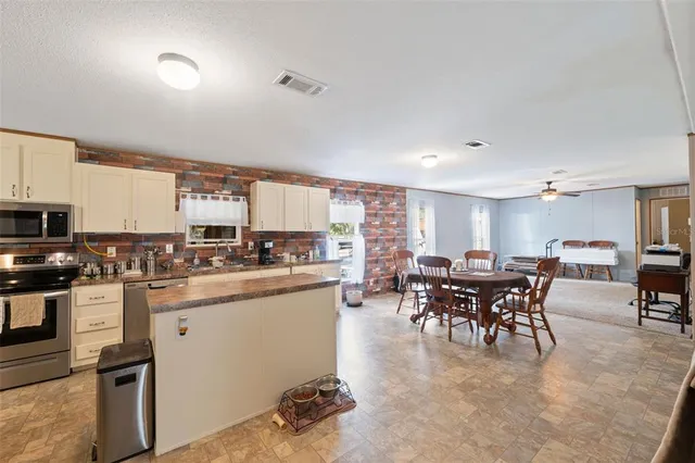 a kitchen with stainless steel appliances granite countertop sink stove and white cabinets with wooden floor